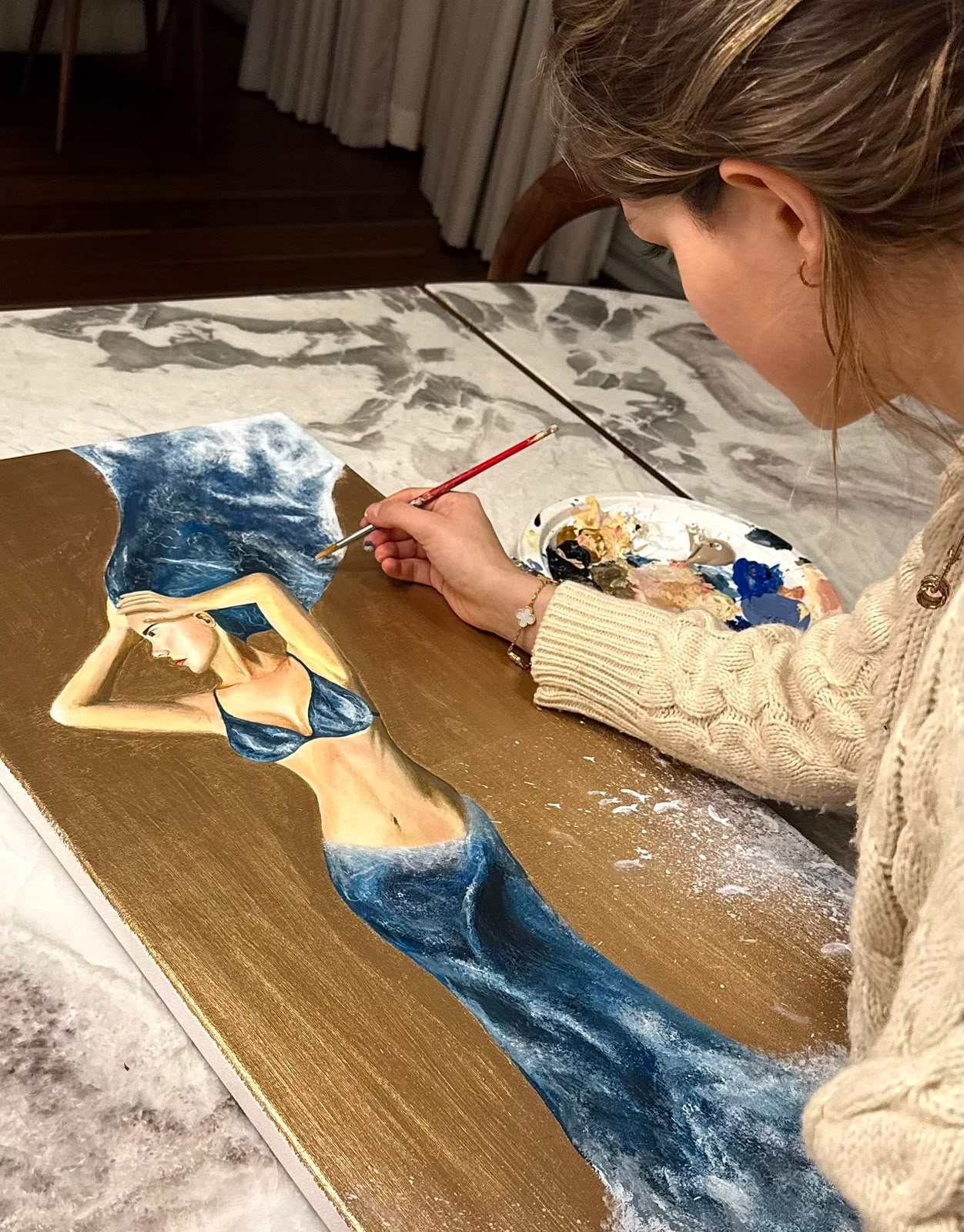 Anemca au travail sur une toile à fond doré : une silhouette de femme vêtue de vagues